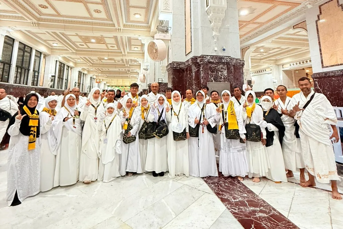 Kelompok jamaah umroh Jannah Firdaus Travel sedang berdoa bersama di Masjidil Haram dengan latar belakang Ka'bah yang megah